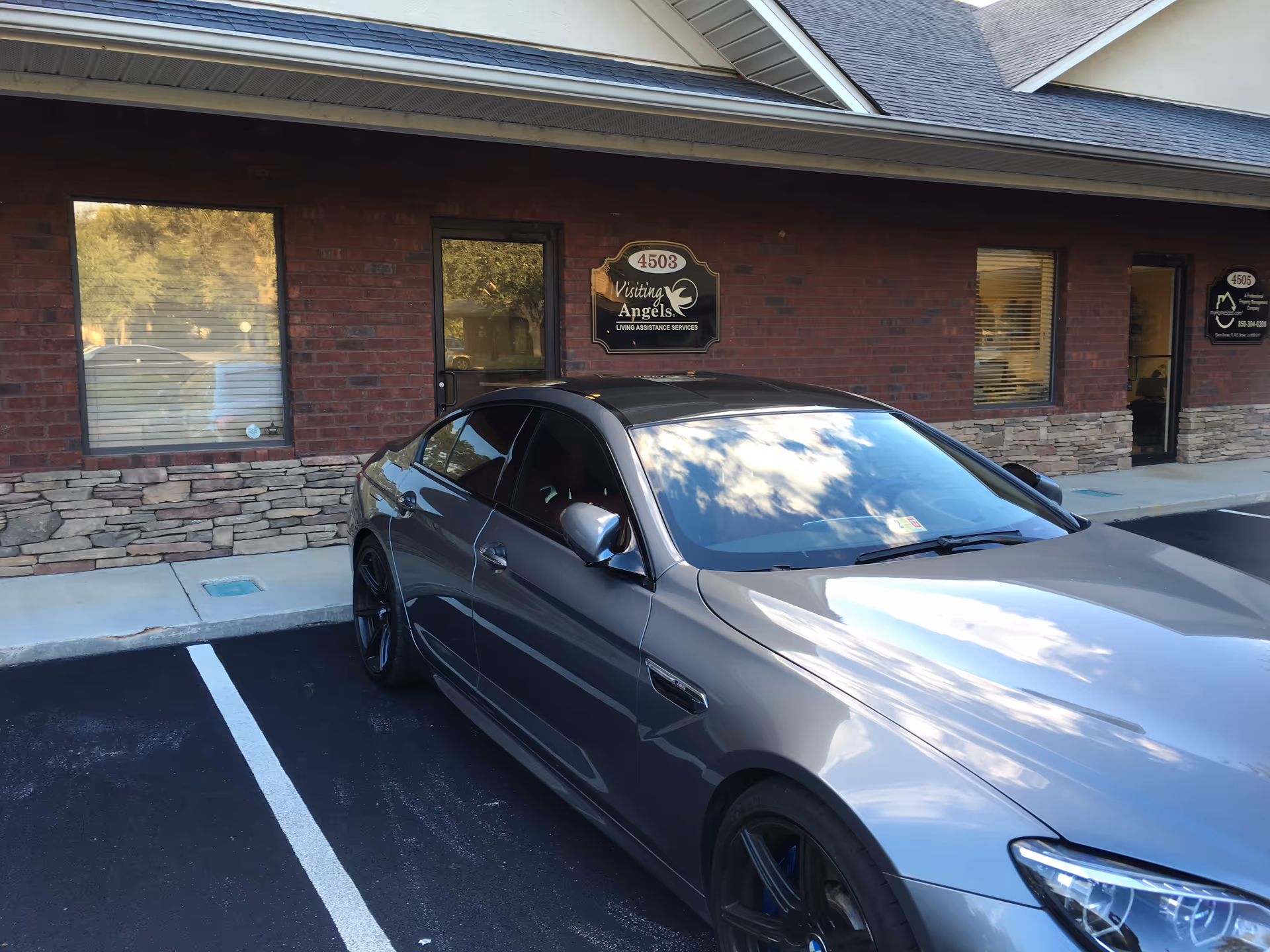 Silver car parked in front of Visiting Angels facility with brick exterior.