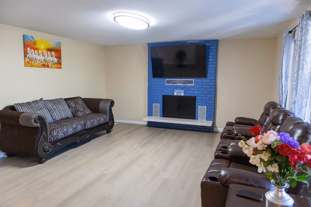 Living room with brown leather sofas, a blue brick fireplace, and a mounted TV.