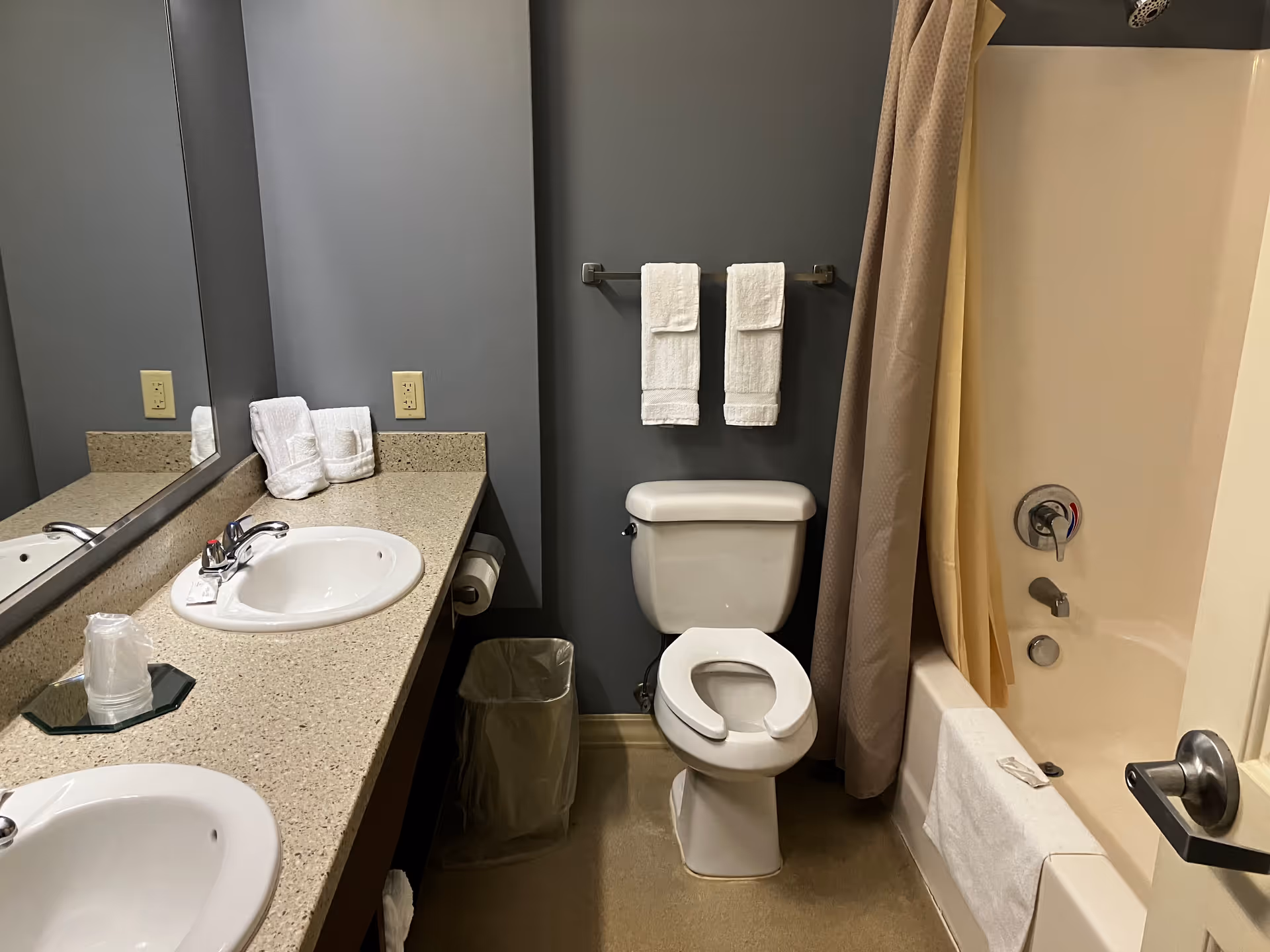 Shared bathroom with double sink vanity, toilet, and tub/shower with a curtain.