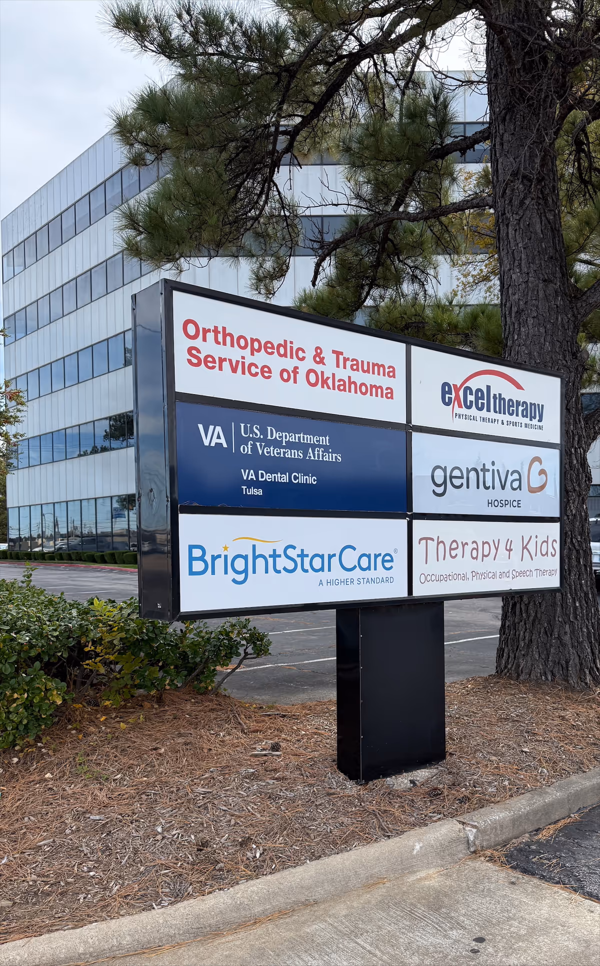 Multi-panel outdoor sign advertising BrightStar Care and other services near a modern building.