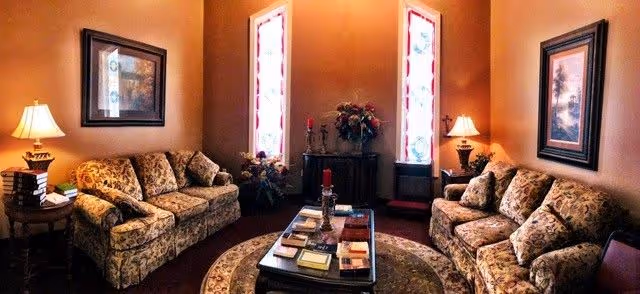 Cozy hospice living room with floral sofas, lamps, framed art, and a central coffee table.