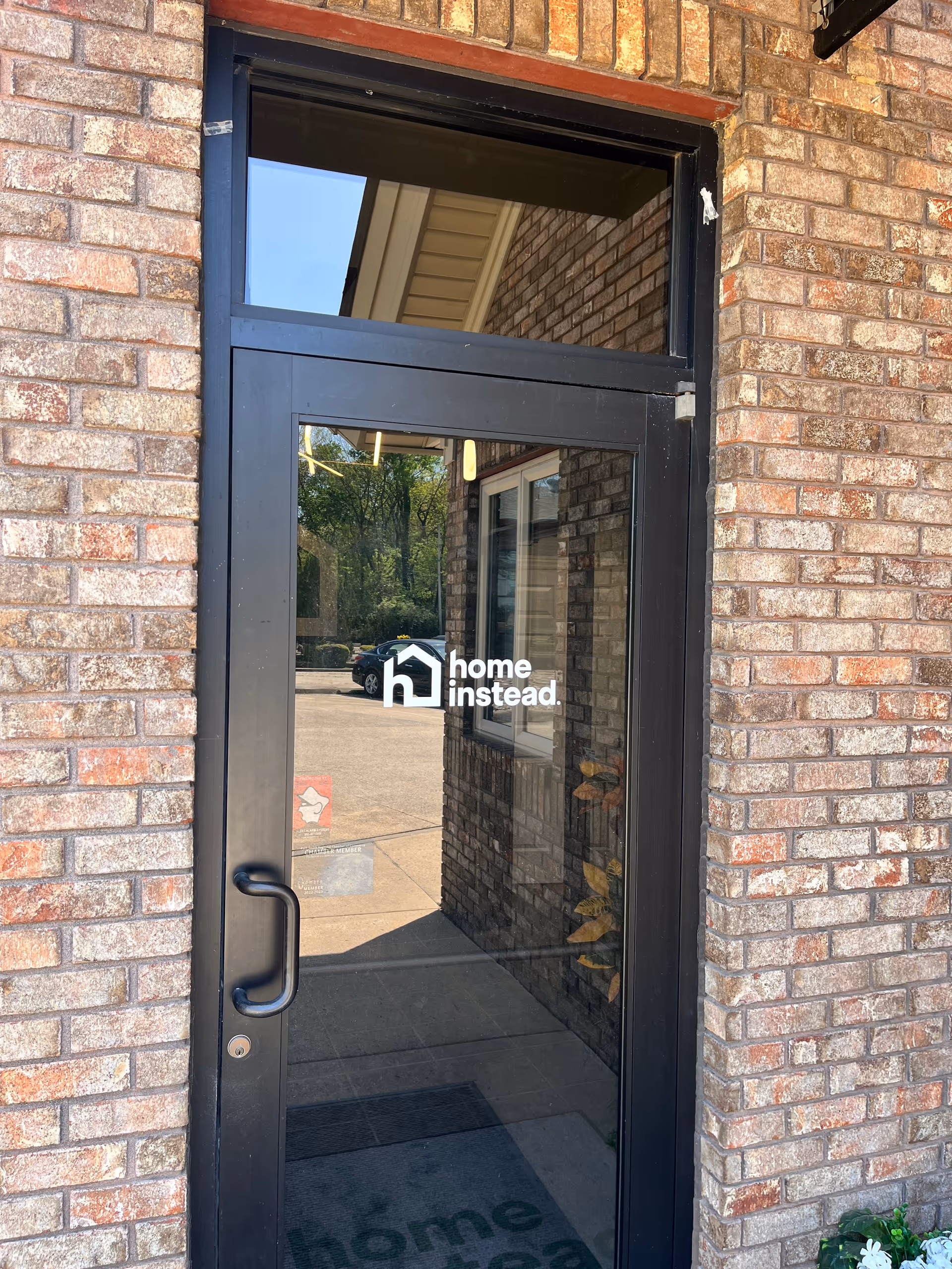 Glass door entrance with Home Instead logo on brick exterior.