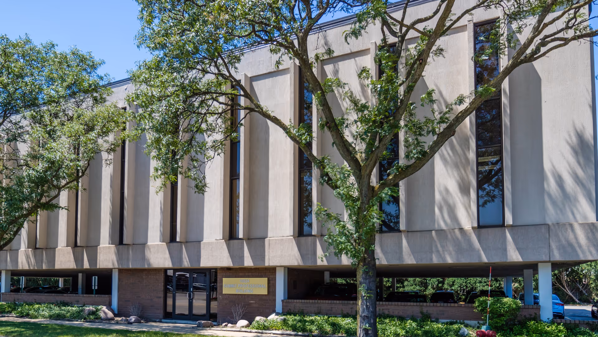 Exterior view of a modern senior living facility with tall windows and trees.