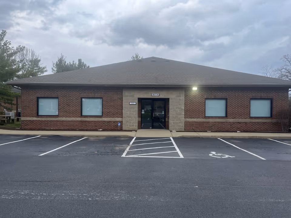 Single-story brick building with a central entrance and accessible parking.