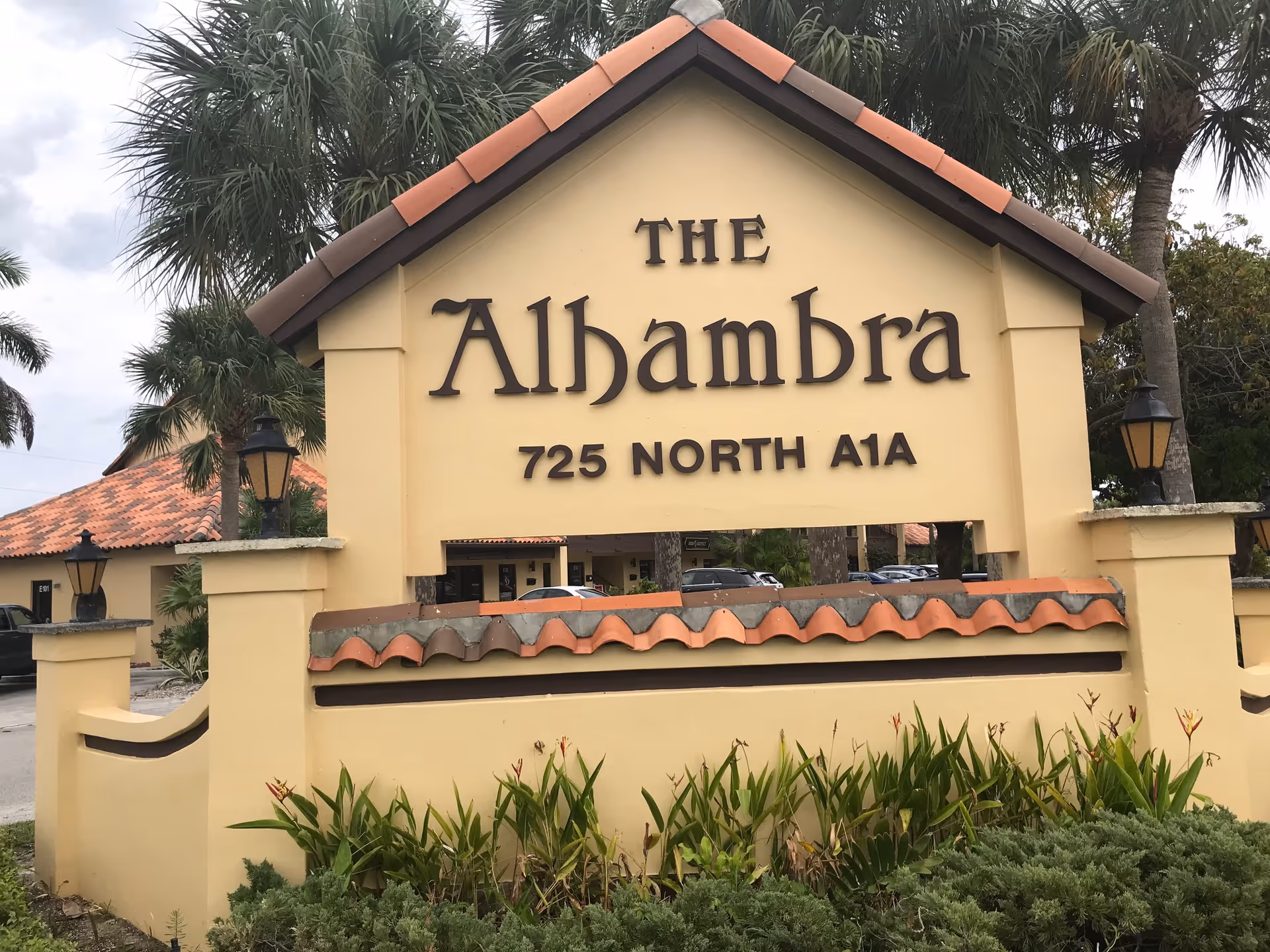 Front view of The Alhambra entrance sign with landscaping and palm trees.