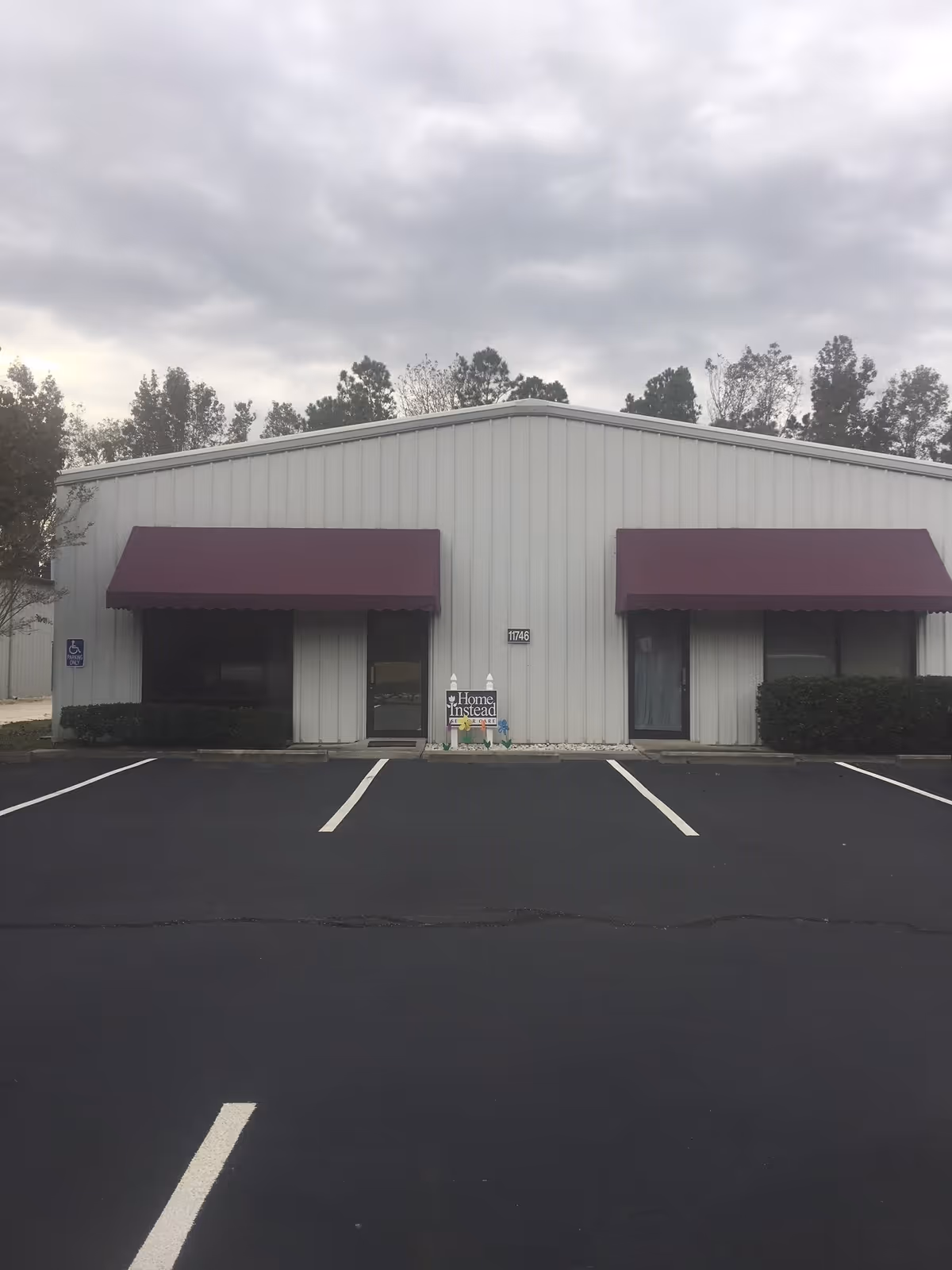 Exterior of a Home Instead facility with purple awnings and a front parking lot.