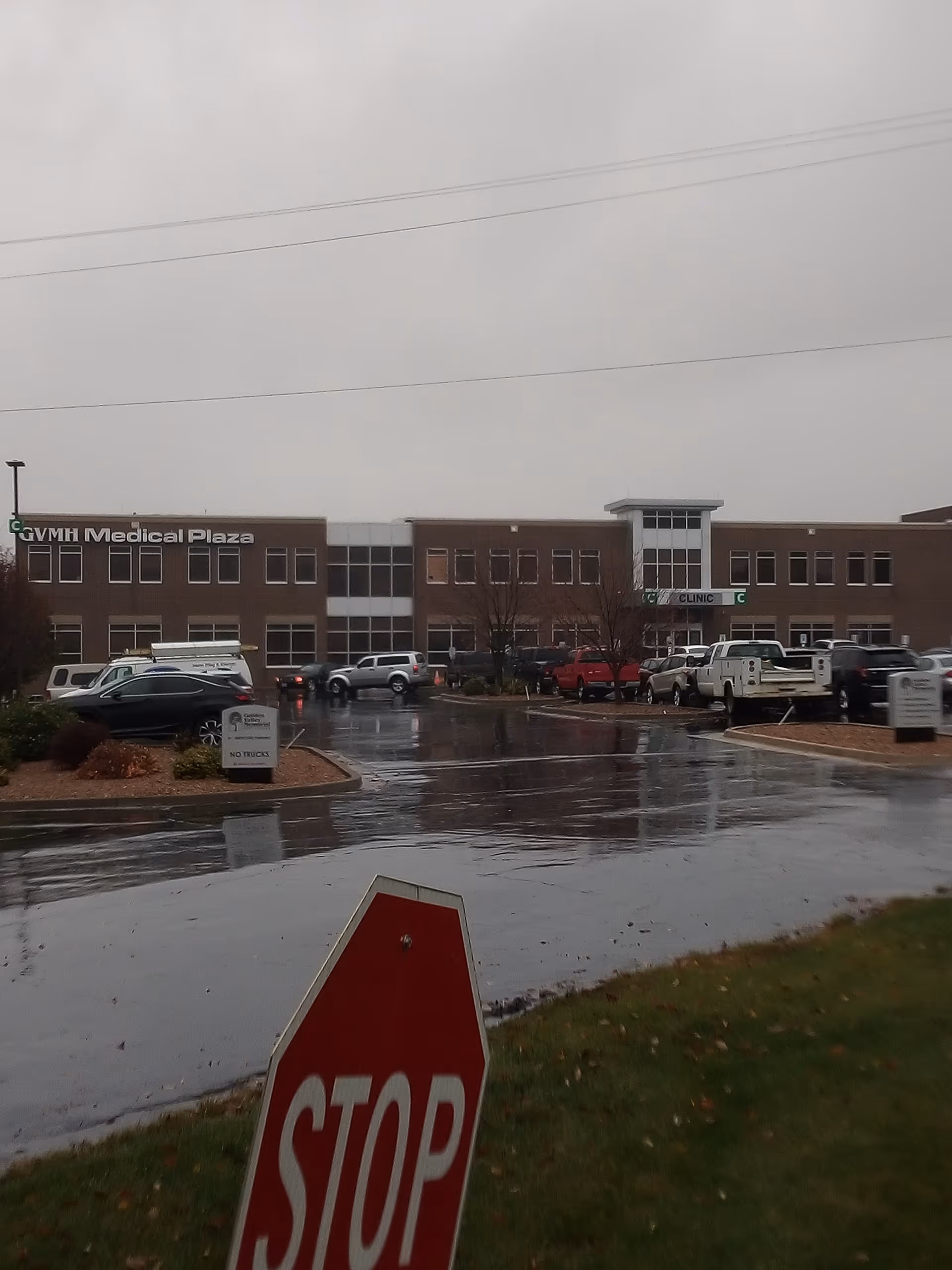 Exterior view of Golden Valley Memorial Healthcare building with a wet parking lot and stop sign.