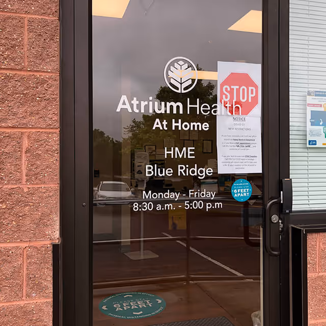 Entrance door for Atrium Health At Home Blue Ridge, displaying hours and notices.