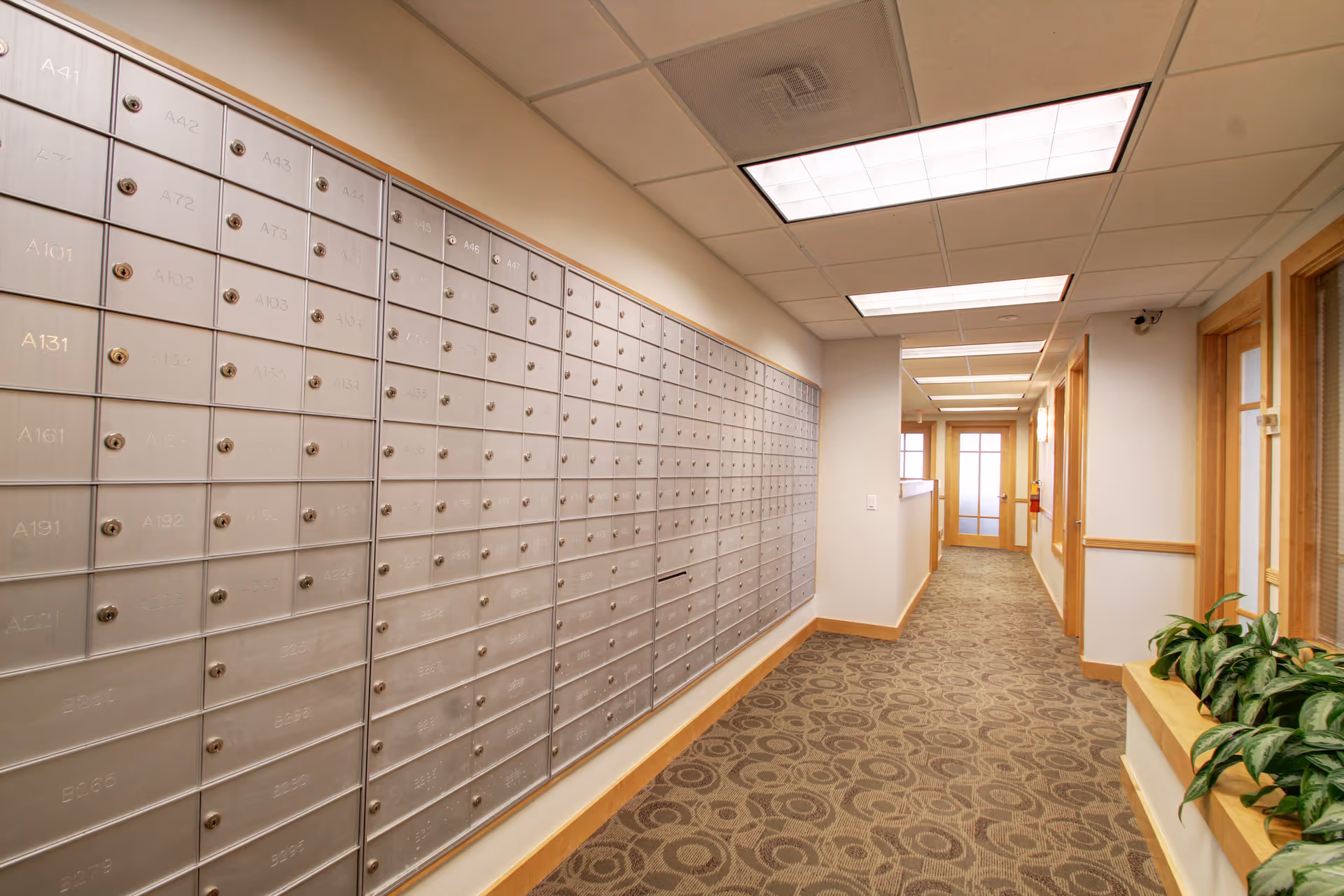 Long indoor hallway in a senior living facility with a row of mailboxes on the left.
