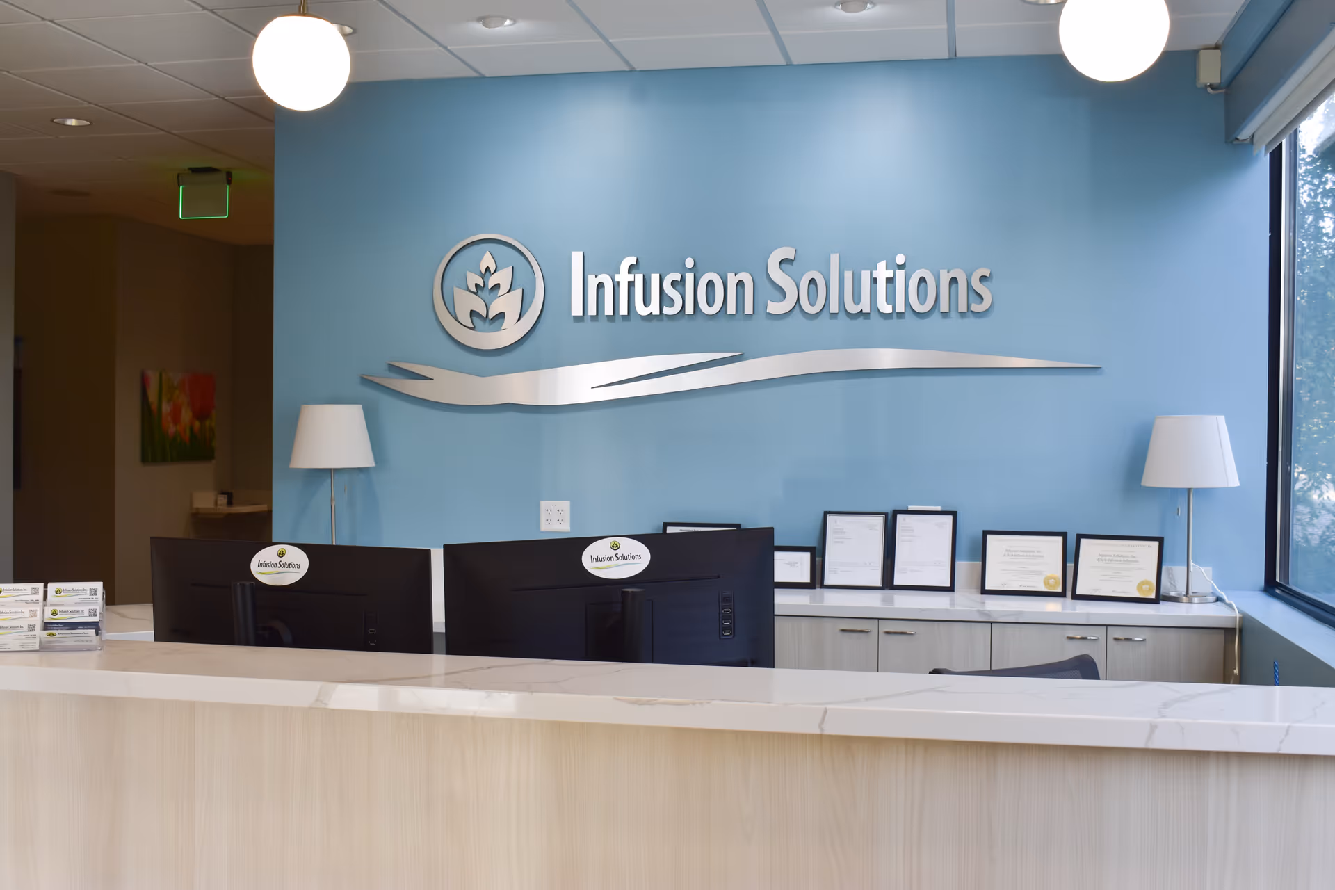 Reception desk in a blue-walled lobby with Infusion Solutions branding.