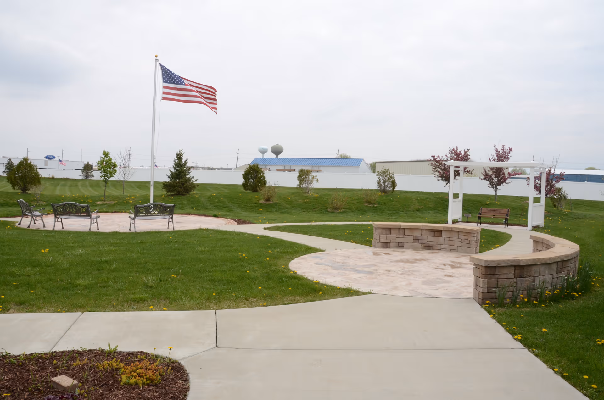 Outdoor courtyard with flag, benches, curved stone seating, and green lawn