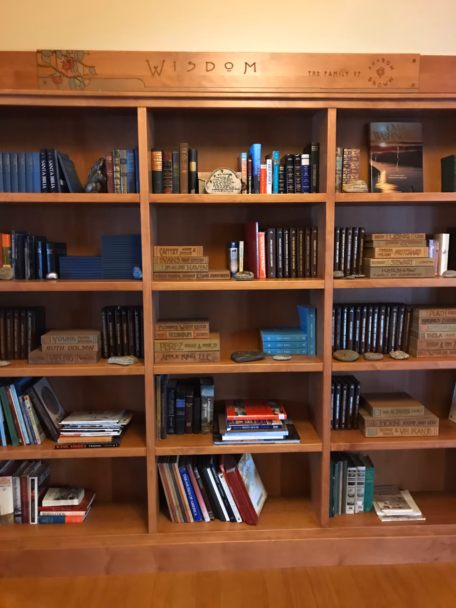 Wooden bookshelf filled with books and decorative stones beneath a 'Wisdom' sign.
