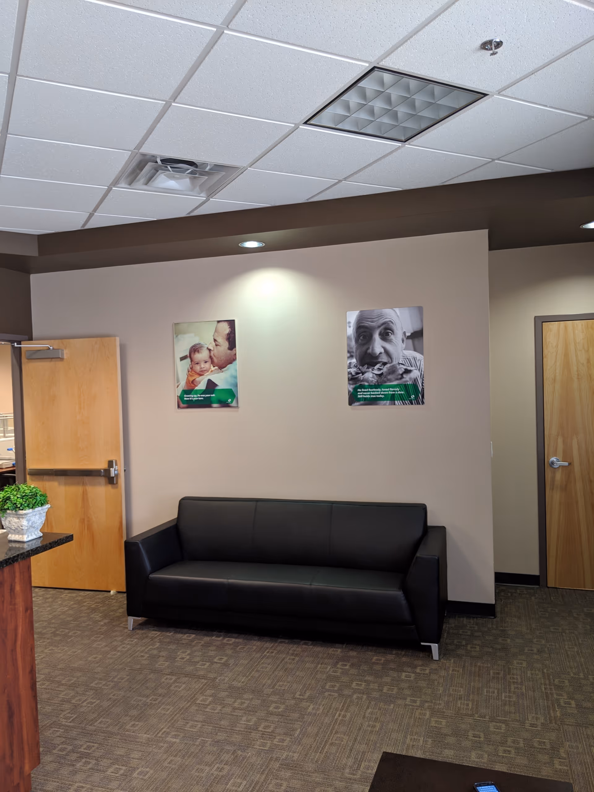 A modern indoor lounge area features a black sofa and wall posters.