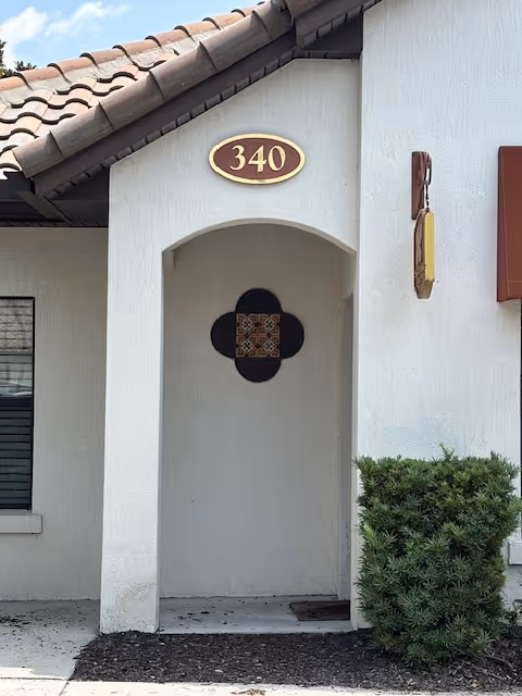 Front entrance of a white stucco building with an arched doorway and 340 plaque.