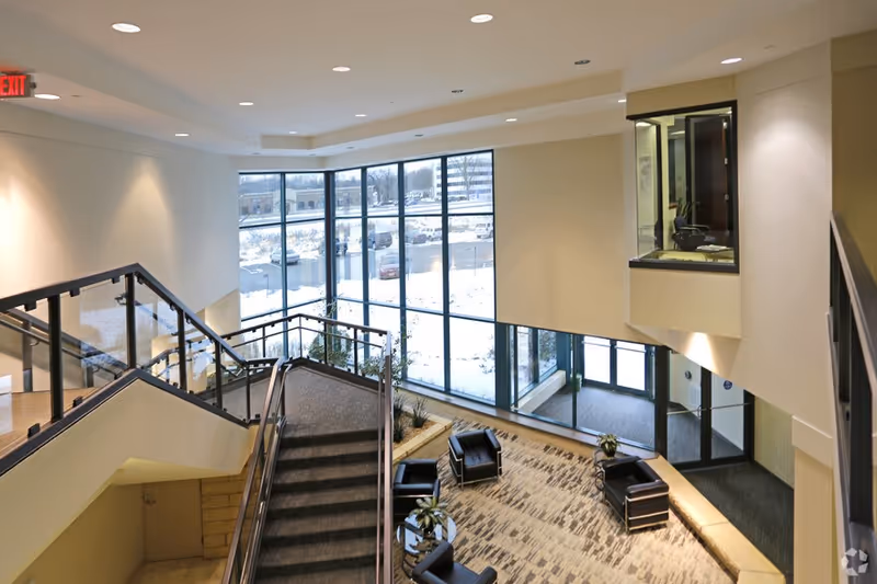 Modern interior lobby with stairs, large windows, and seating.