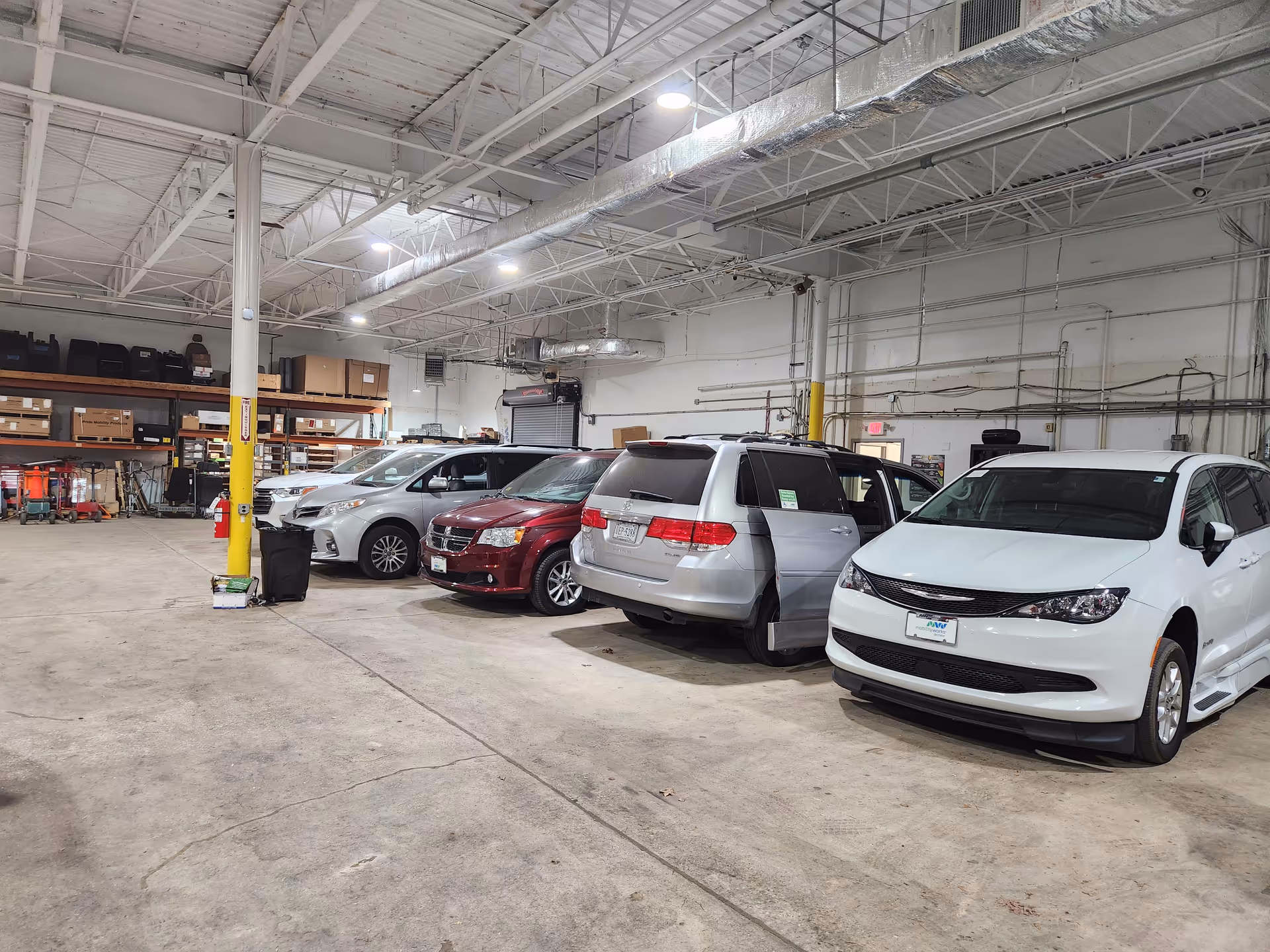 Indoor warehouse with multiple cars parked inside a large industrial space.