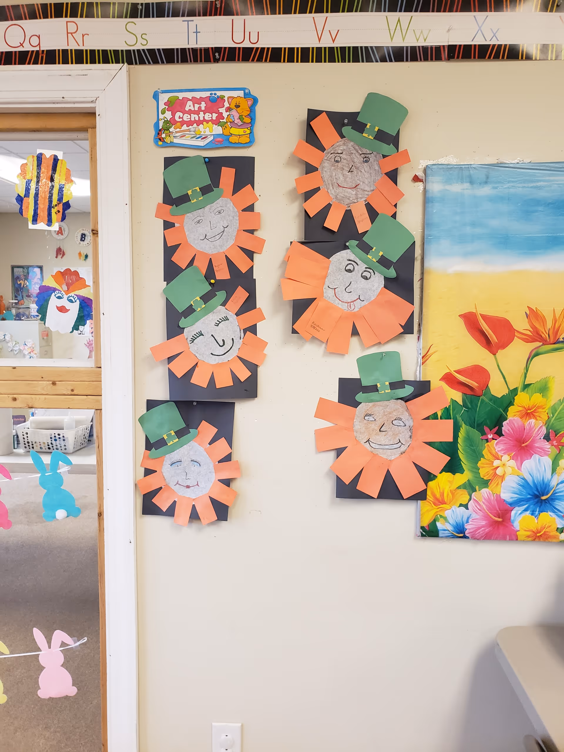 Interior activity room wall displaying orange sun crafts with green hats