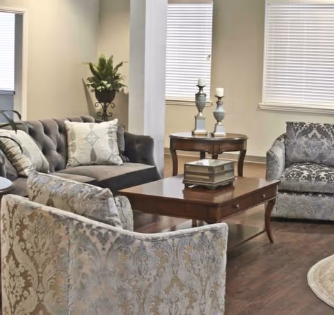 Cozy hospice living room with patterned sofas, chairs, and a wooden coffee table.