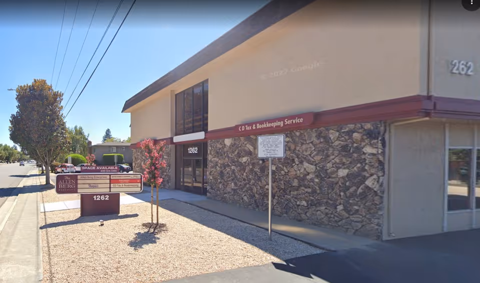 Exterior view of a tan building with a stone lower wall and front entrance.