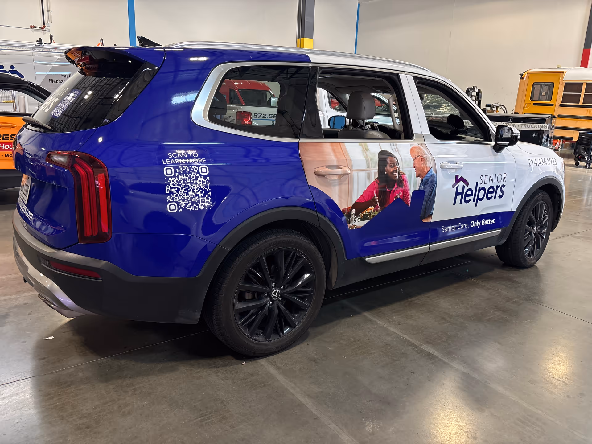 Blue Senior Helpers branded SUV inside a large indoor facility with other vehicles nearby.