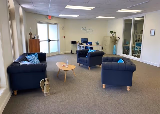 Interior lounge at Visiting Angels with blue tufted sofas and a round coffee table.