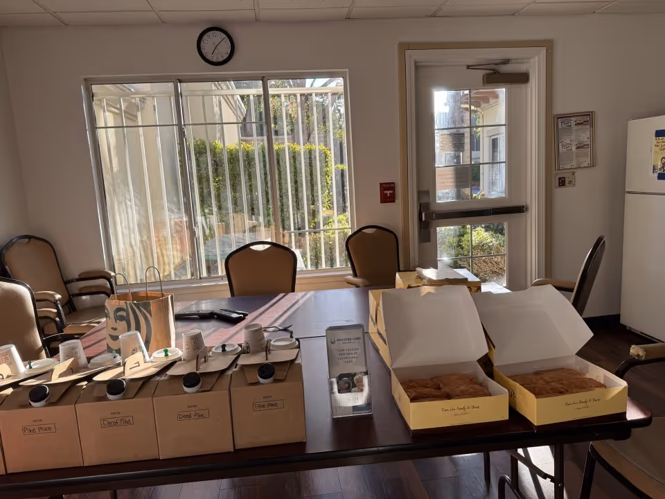 Pastry boxes and mugs arranged on a long dining room table.
