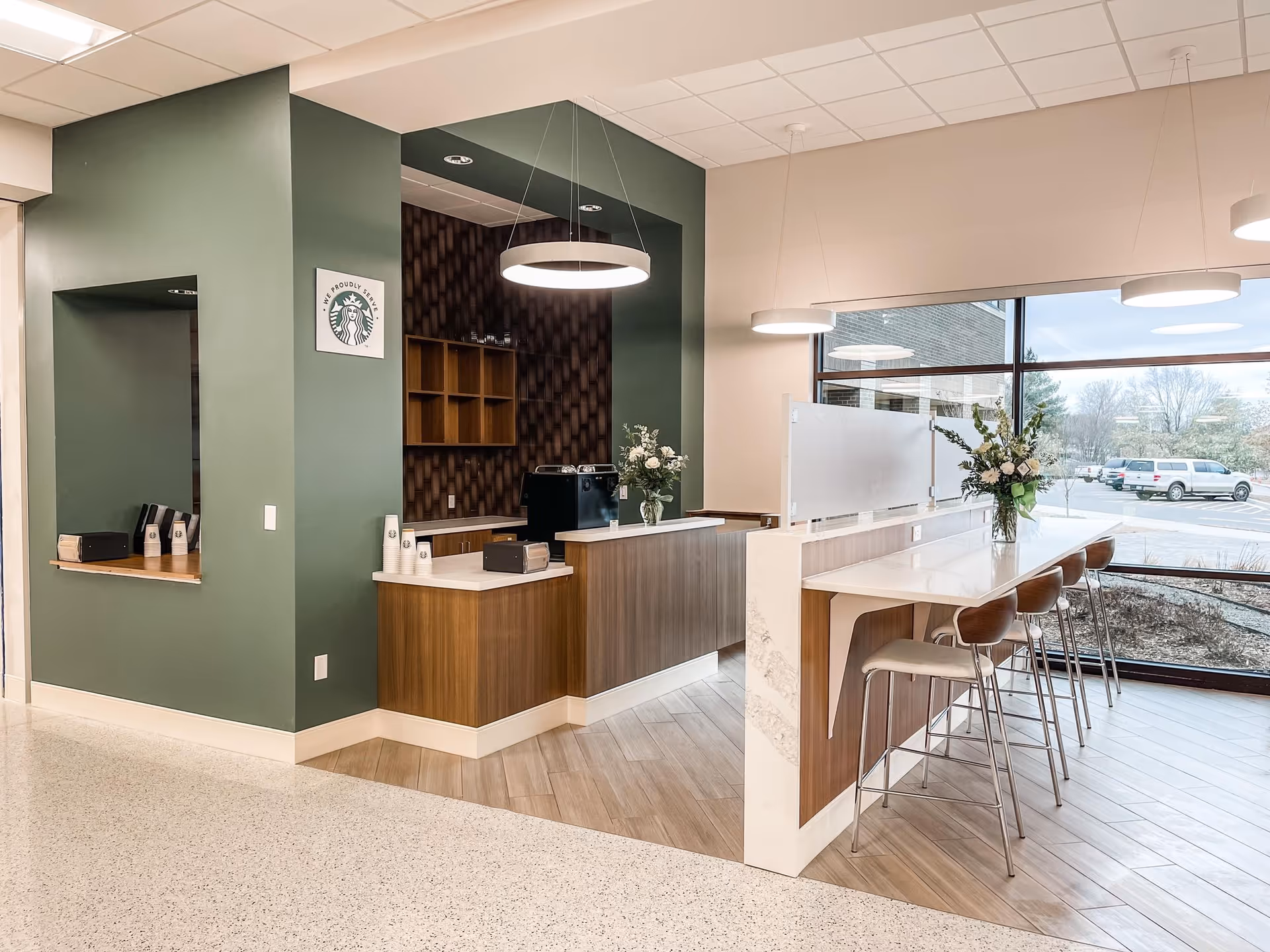 Modern reception area with a long marble counter, plants, and bar stools by windows.