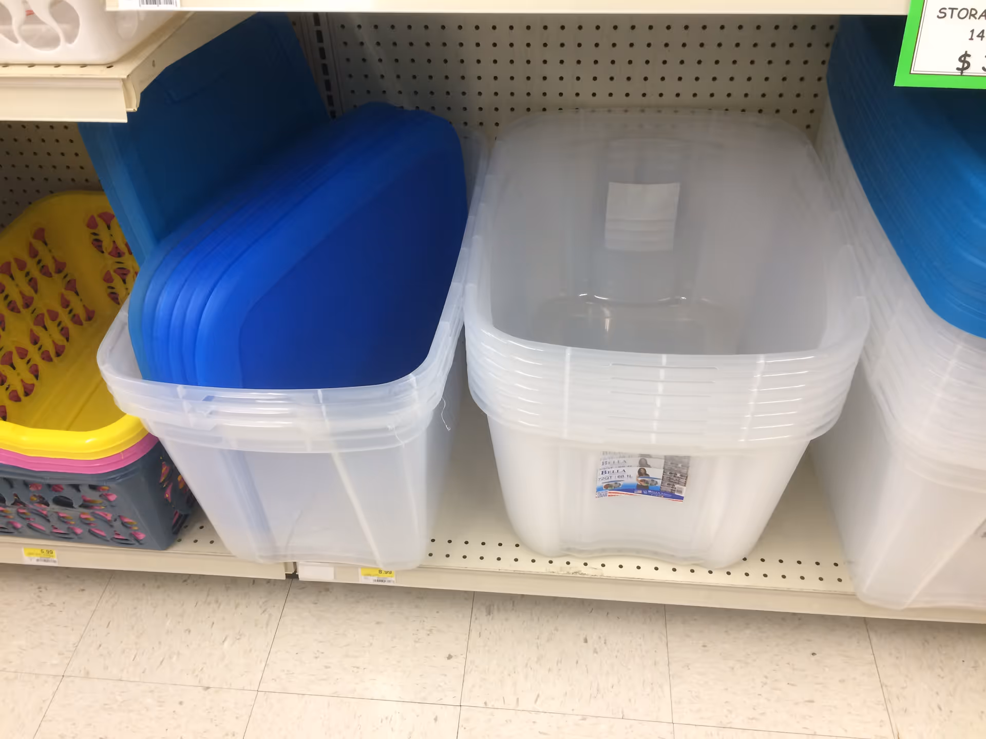 Plastic storage bins with blue lids stacked on a store shelf inside Discount Drug Mart.