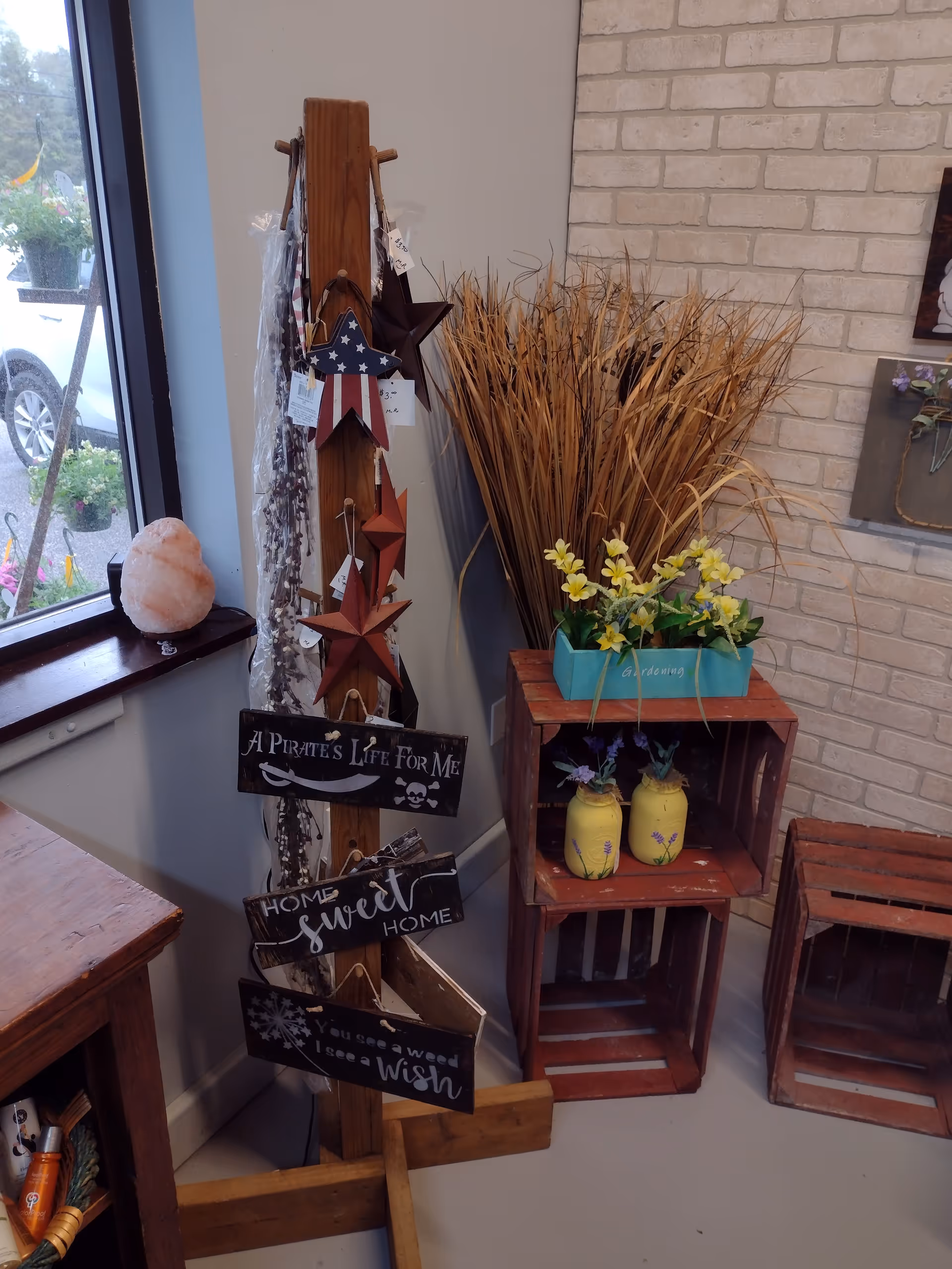 Indoor corner with rustic decor, star ornaments, dried grasses, and potted yellow flowers.