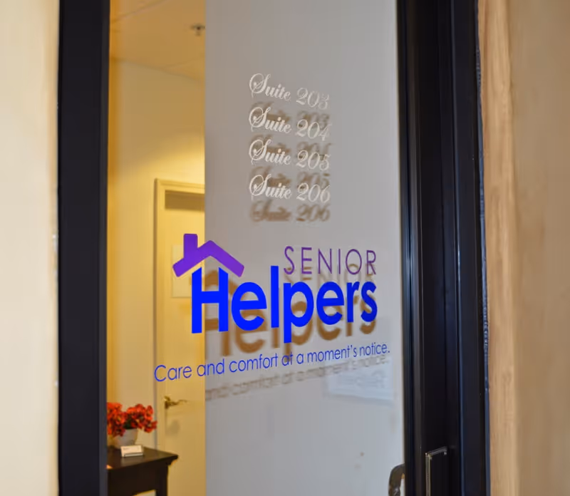 Glass door displays Senior Helpers logo and suite numbers inside a hallway.