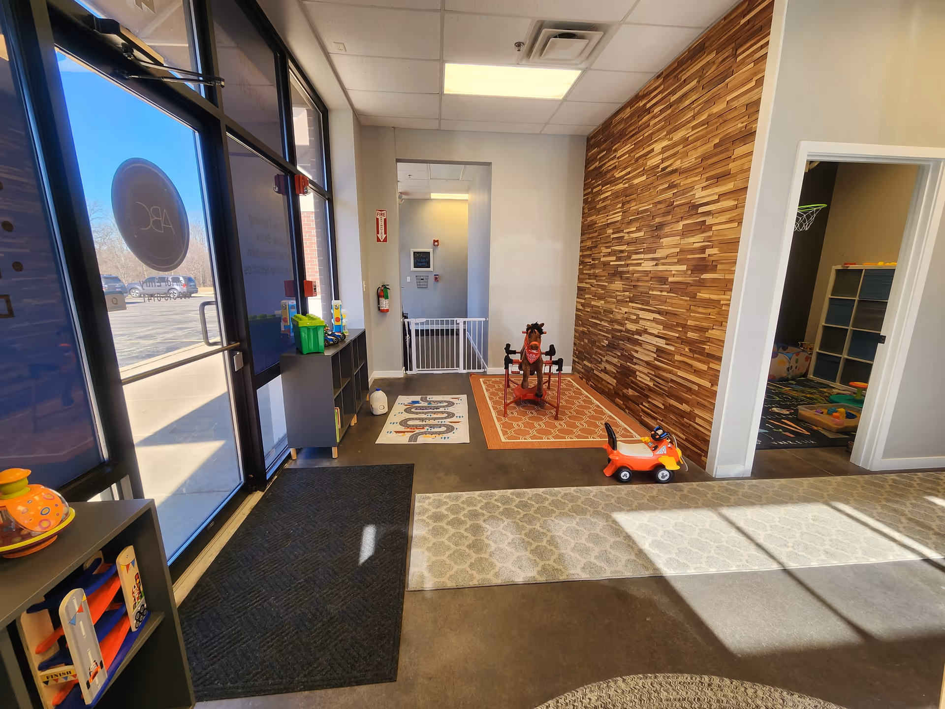 Bright senior living lobby with a children's play area, toys, and wood-accent wall.