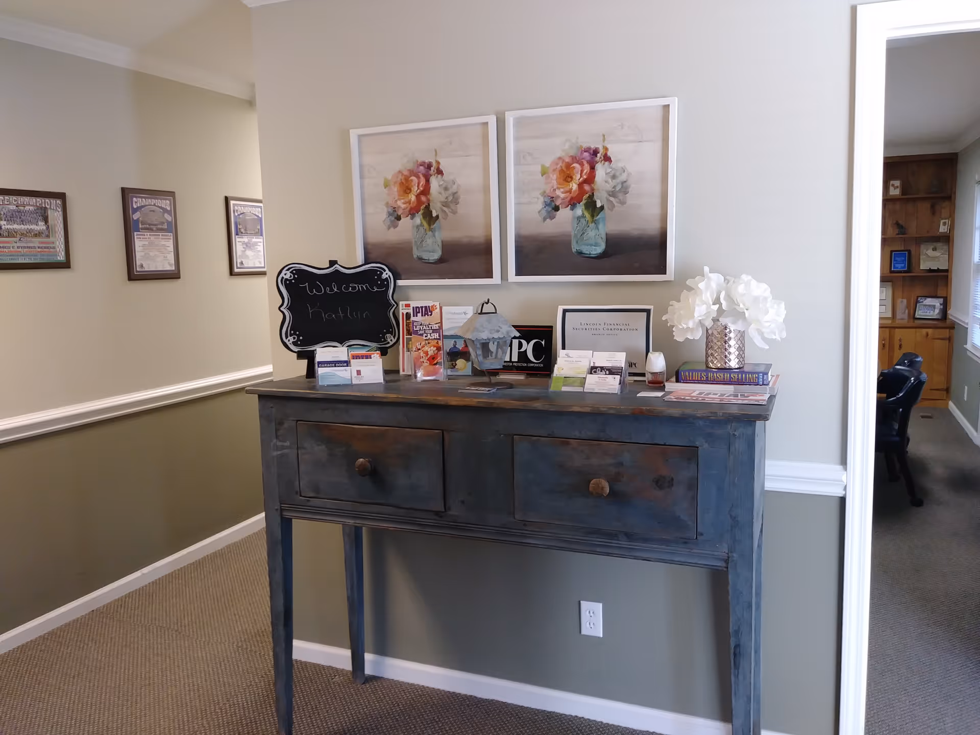 Blue distressed console table with brochures and flowers in a welcoming hallway.