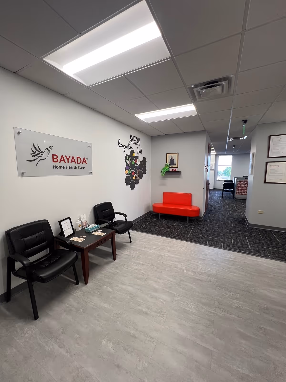 Lobby area with black chairs, a red sofa, and BAYADA sign on the wall.