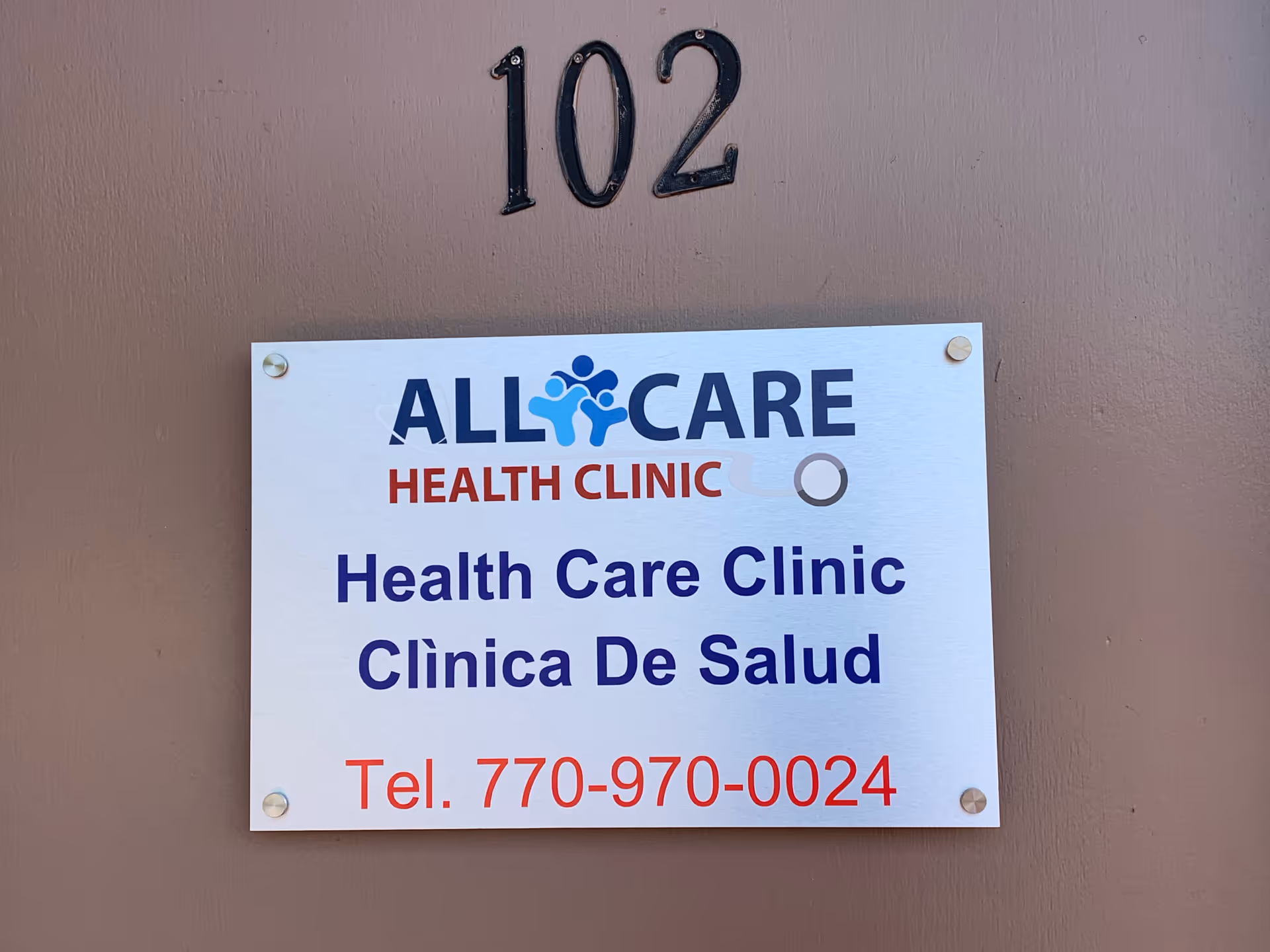  exterior wall with a sign for All Care Health Clinic and unit 102.