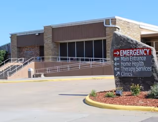 Exterior view of a brick medical facility with a wheelchair ramp and emergency sign