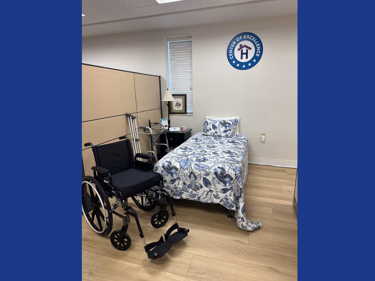 Bedroom in a senior living facility with a bed, wheelchair, and walker.
