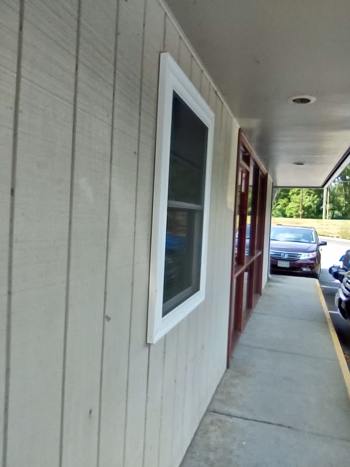 Exterior view of a LINCARE facility with siding, window, door, and parked cars.