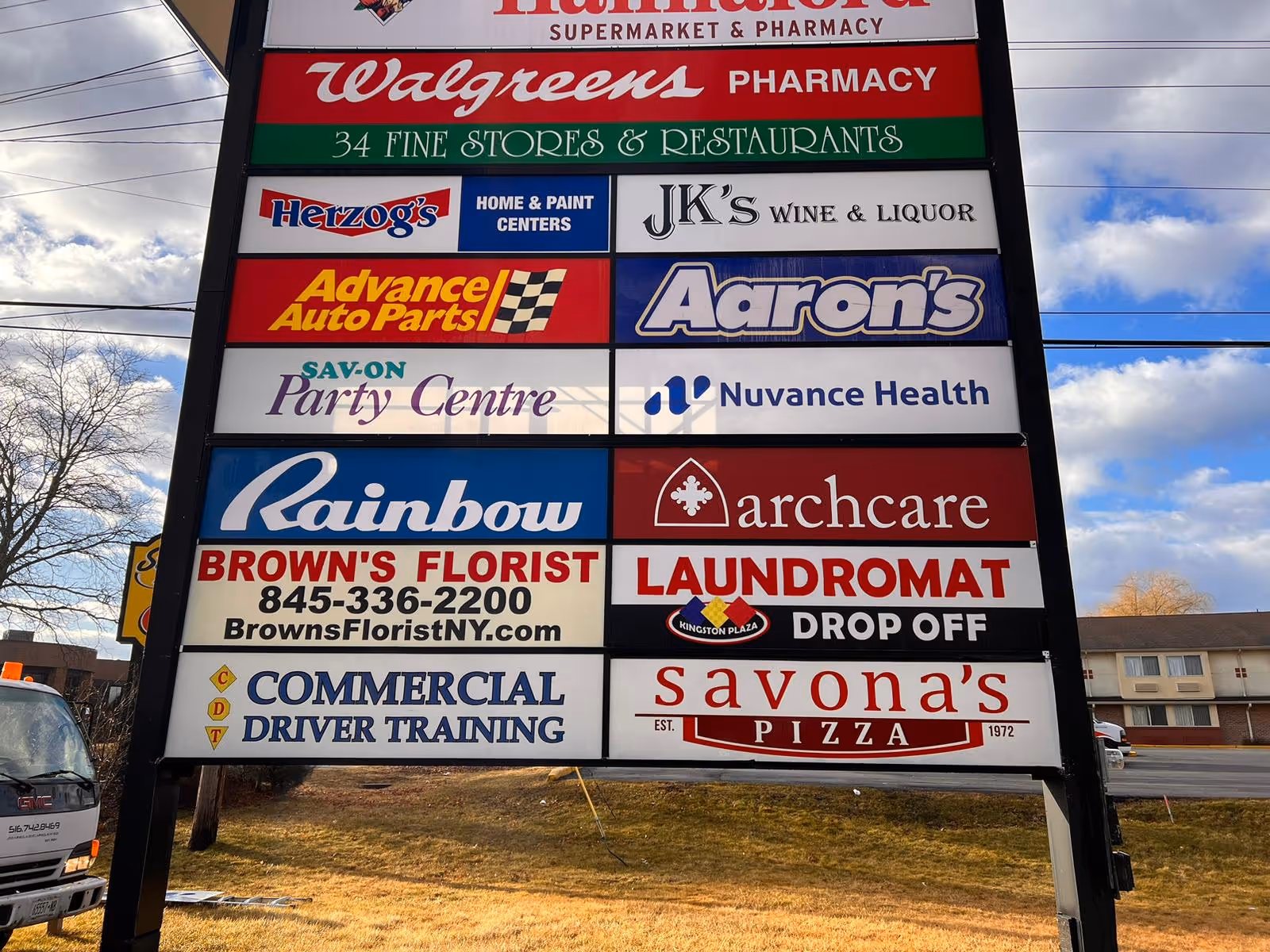 Tall outdoor signboard displaying various business logos, including Walgreens and Browns Florist.