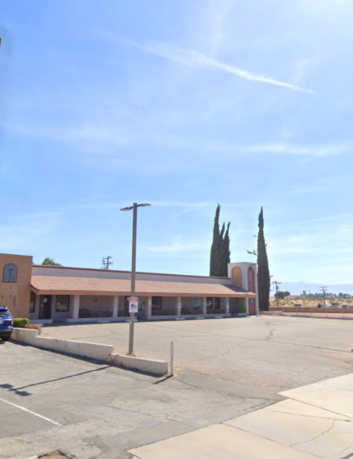 Single-story beige senior living facility with a covered entrance and adjacent parking.