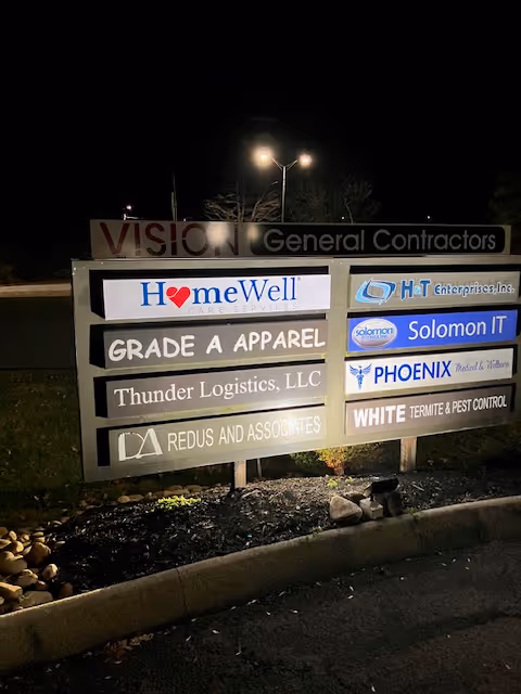Nighttime outdoor signboard displaying HomeWell Care Services among other business signs.
