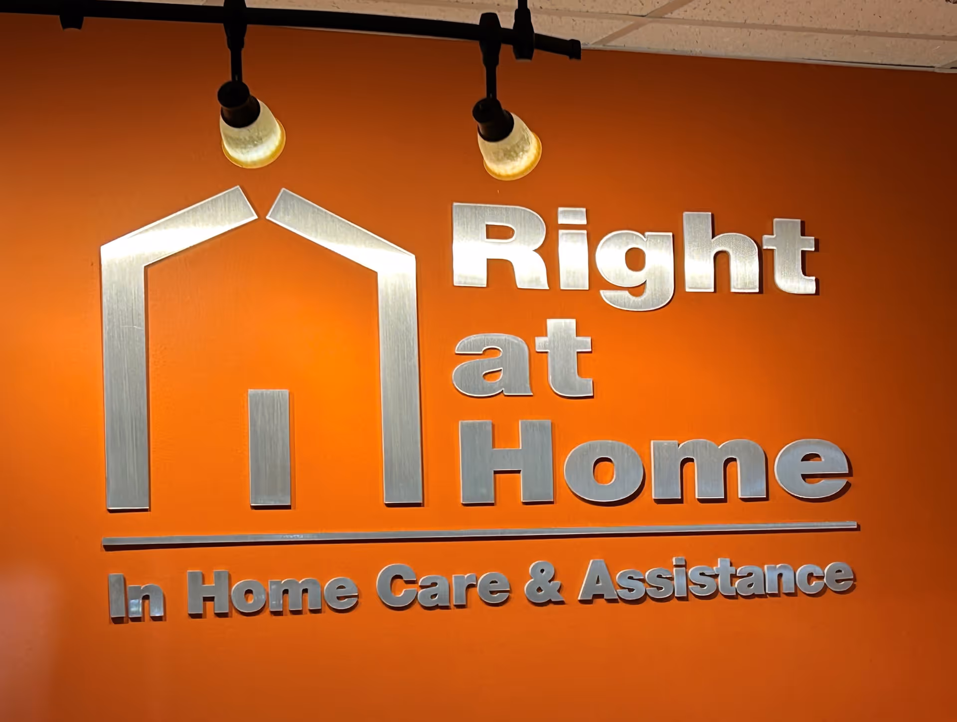 Orange wall displaying the Right at Home logo and the words In Home Care & Assistance.