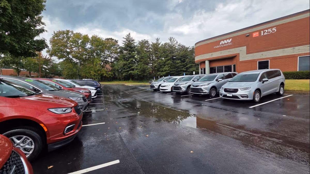 Parking lot with several cars in front of a MobilityWorks building.