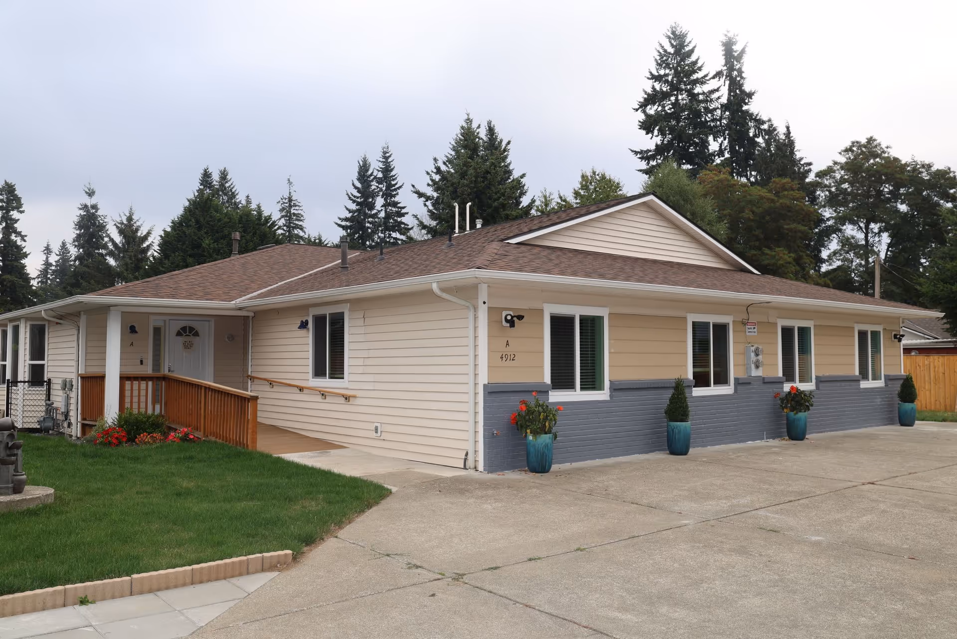 A single-story beige facility with a brown roof, white trim, and potted plants along the front.