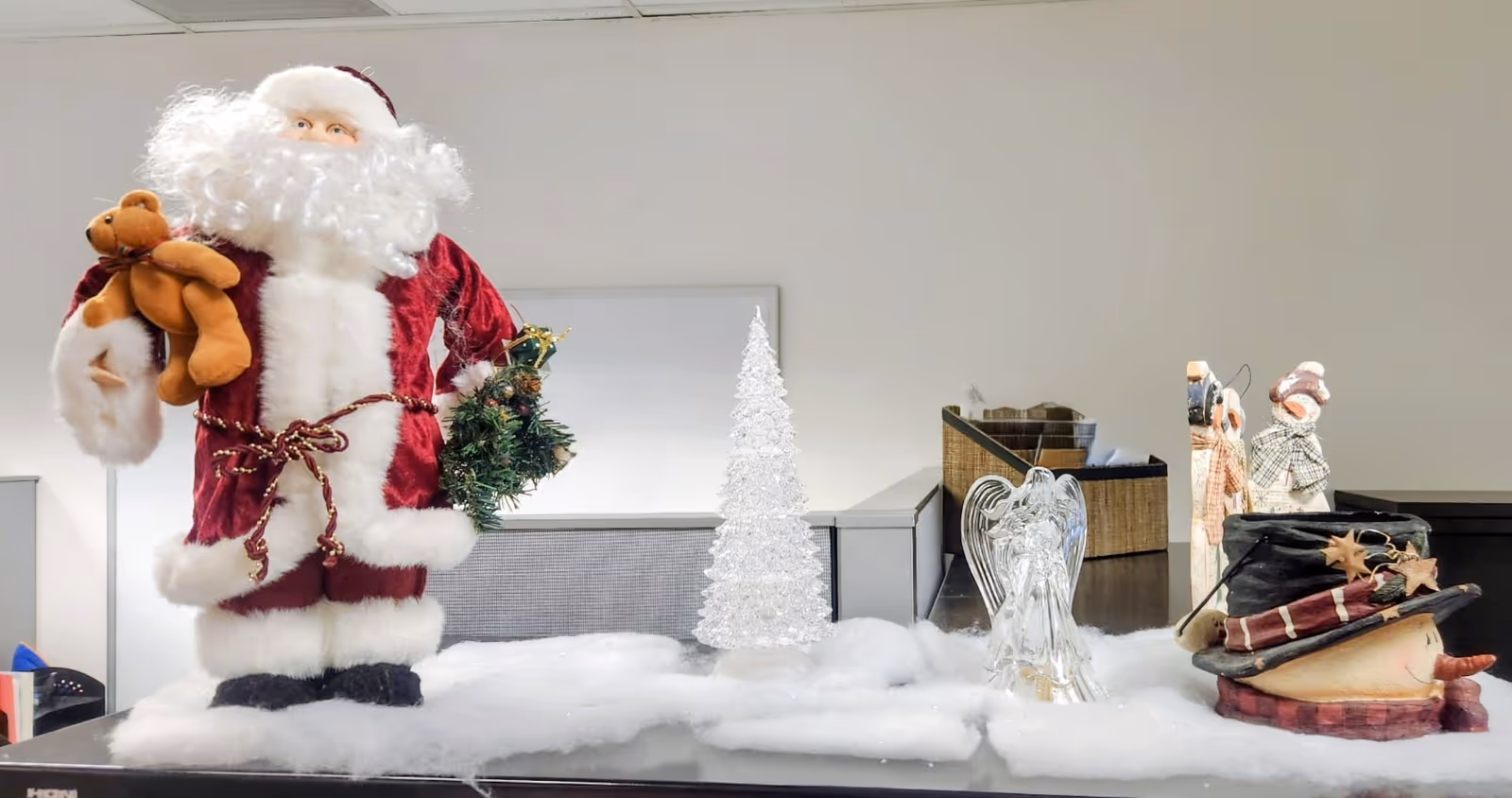 Indoor desk scene with a Santa figure, seasonal decorations, and cotton snowy accents.