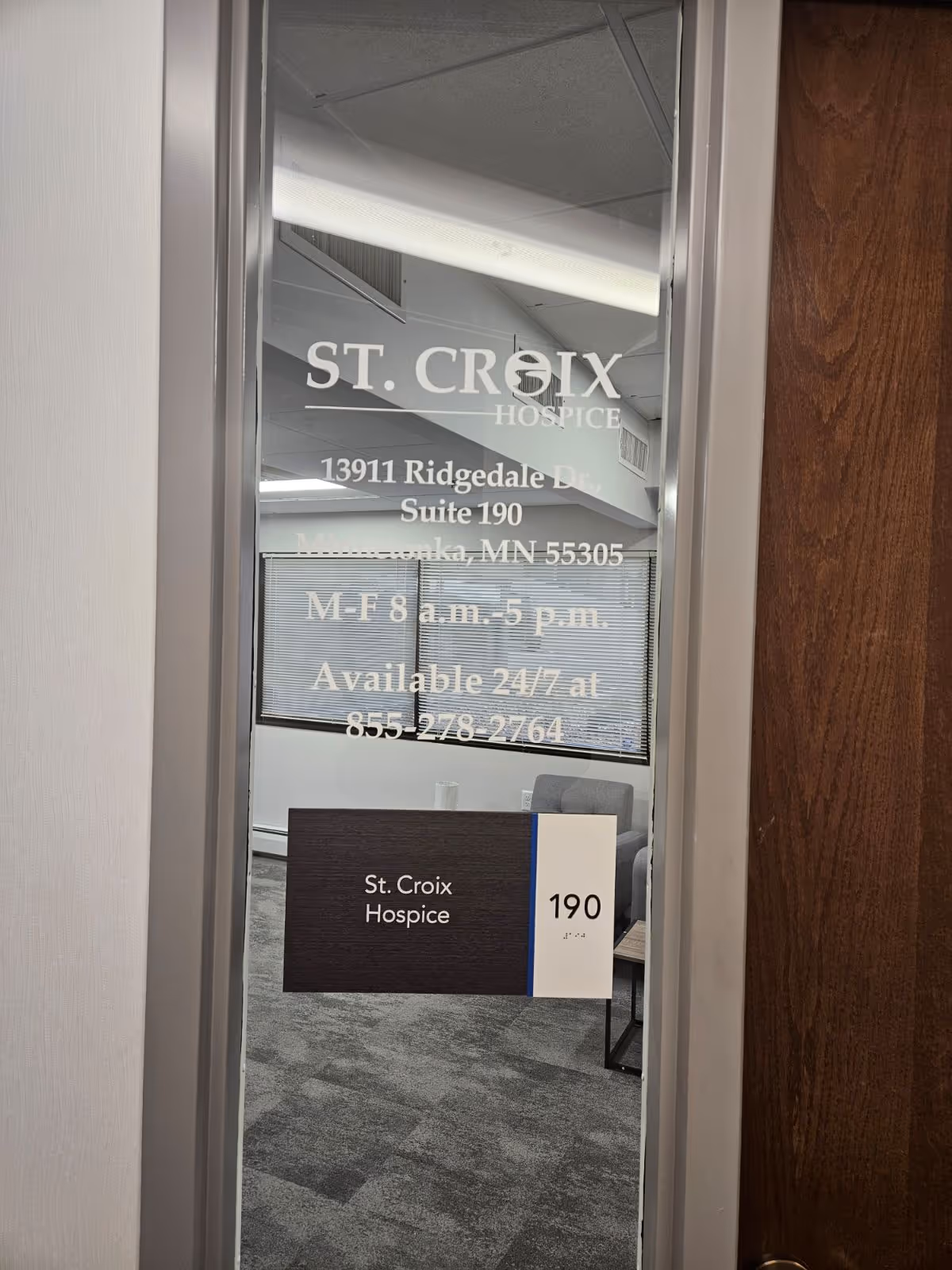 Glass door shows St. Croix Hospice signage and address inside a hallway.