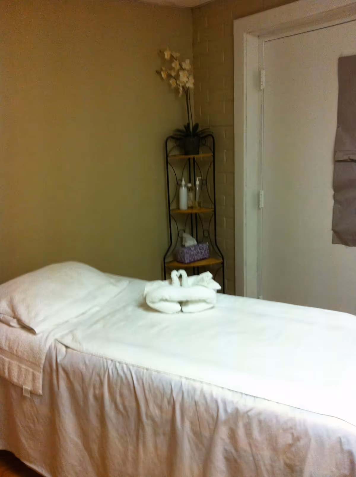Treatment table with folded towel swans in a calm spa-like clinic room.