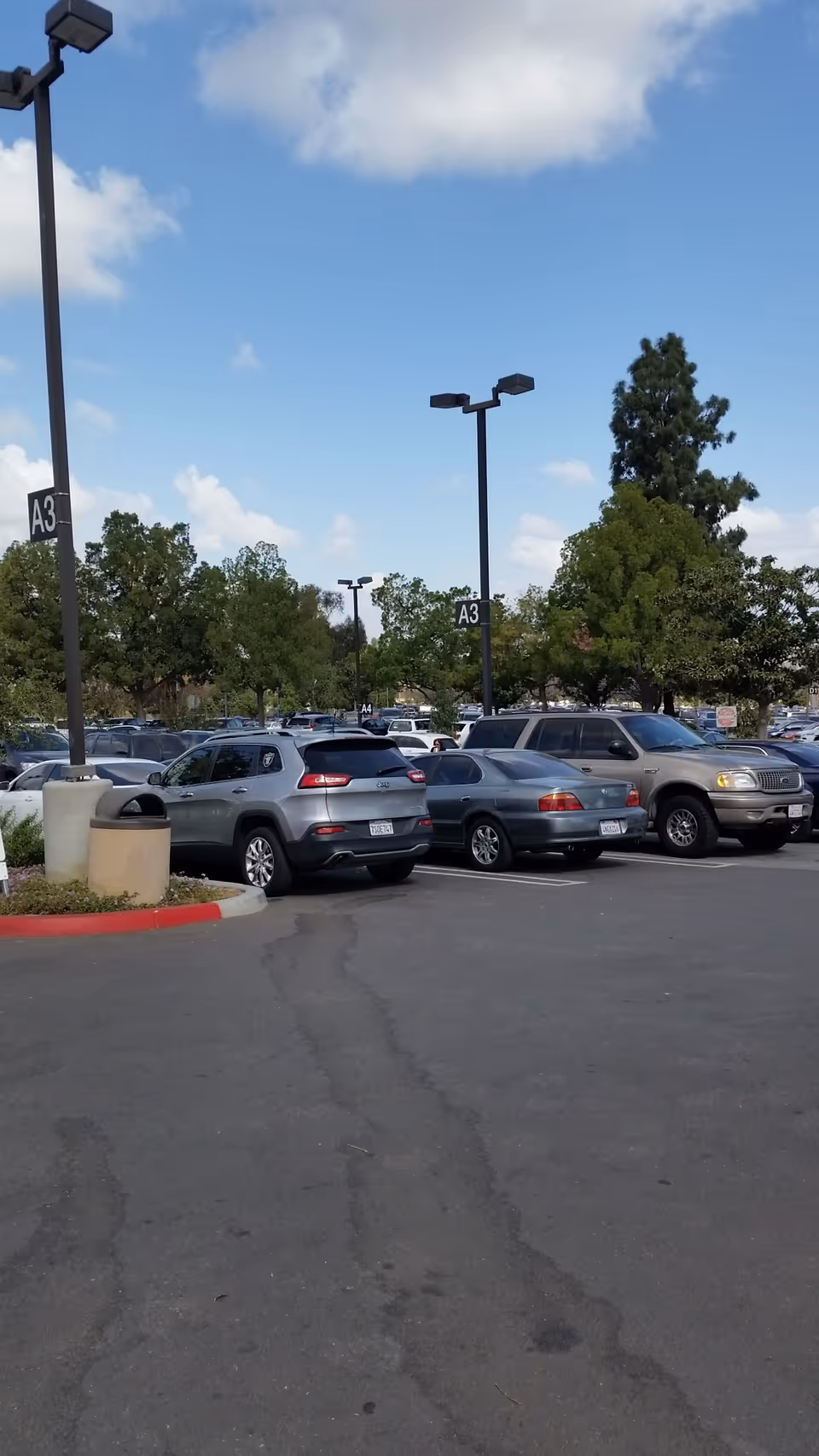 Parking lot outside Redlands Community Hospital with several parked cars and tall street lights.
