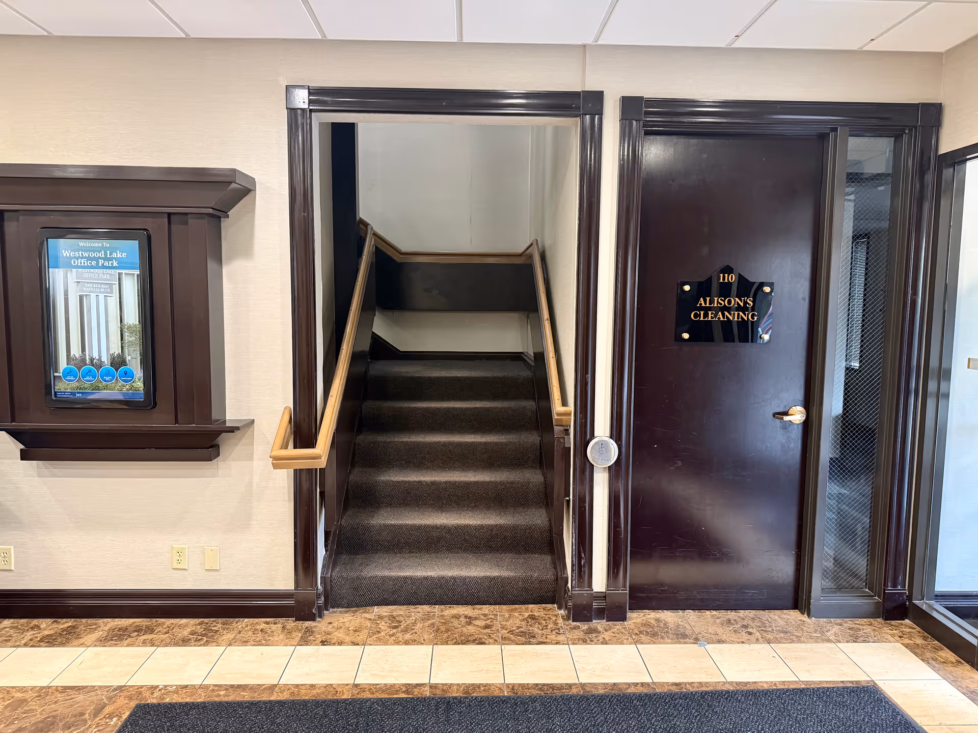 Interior lobby with stairs, a door labeled Alison's Cleaning, and a wall display.