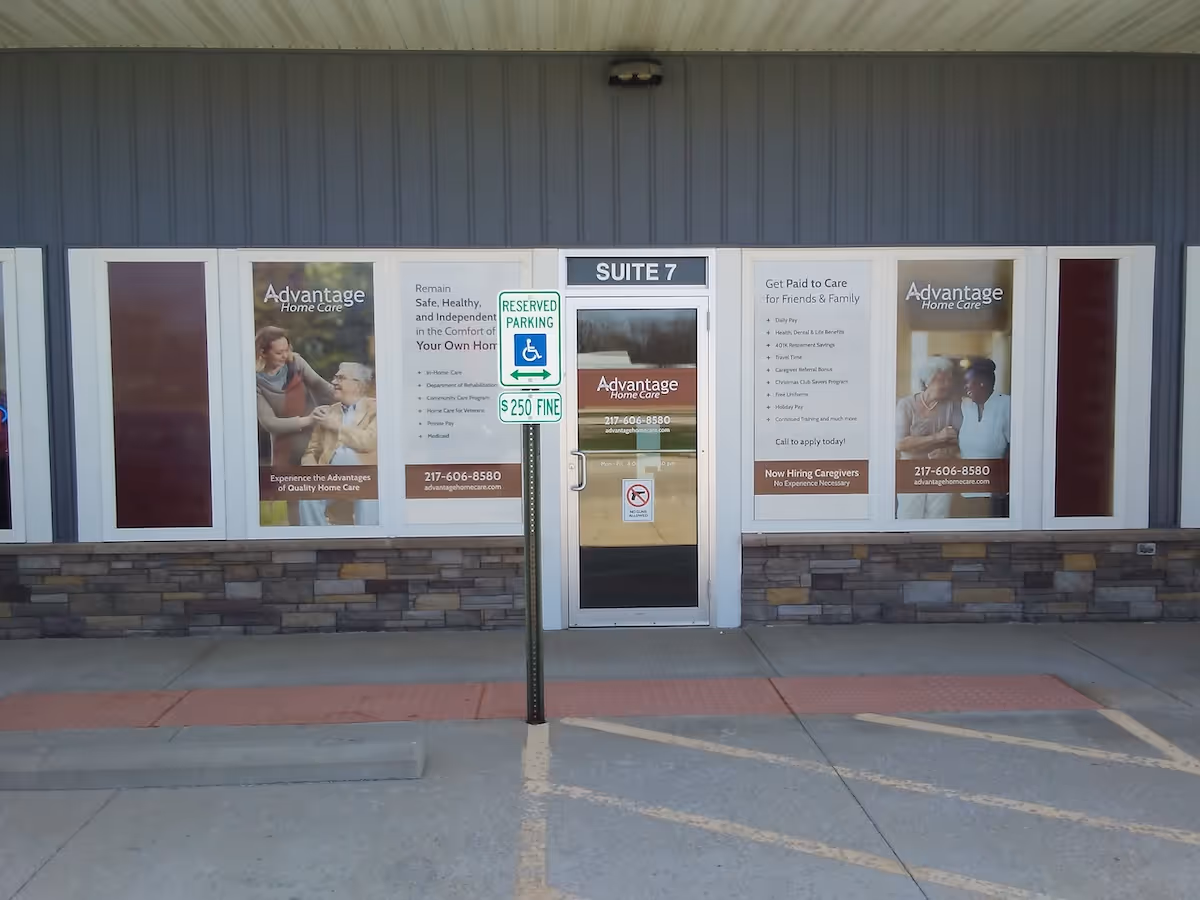 Exterior storefront of Advantage Home Care with posters, glass door, and a handicap parking sign.