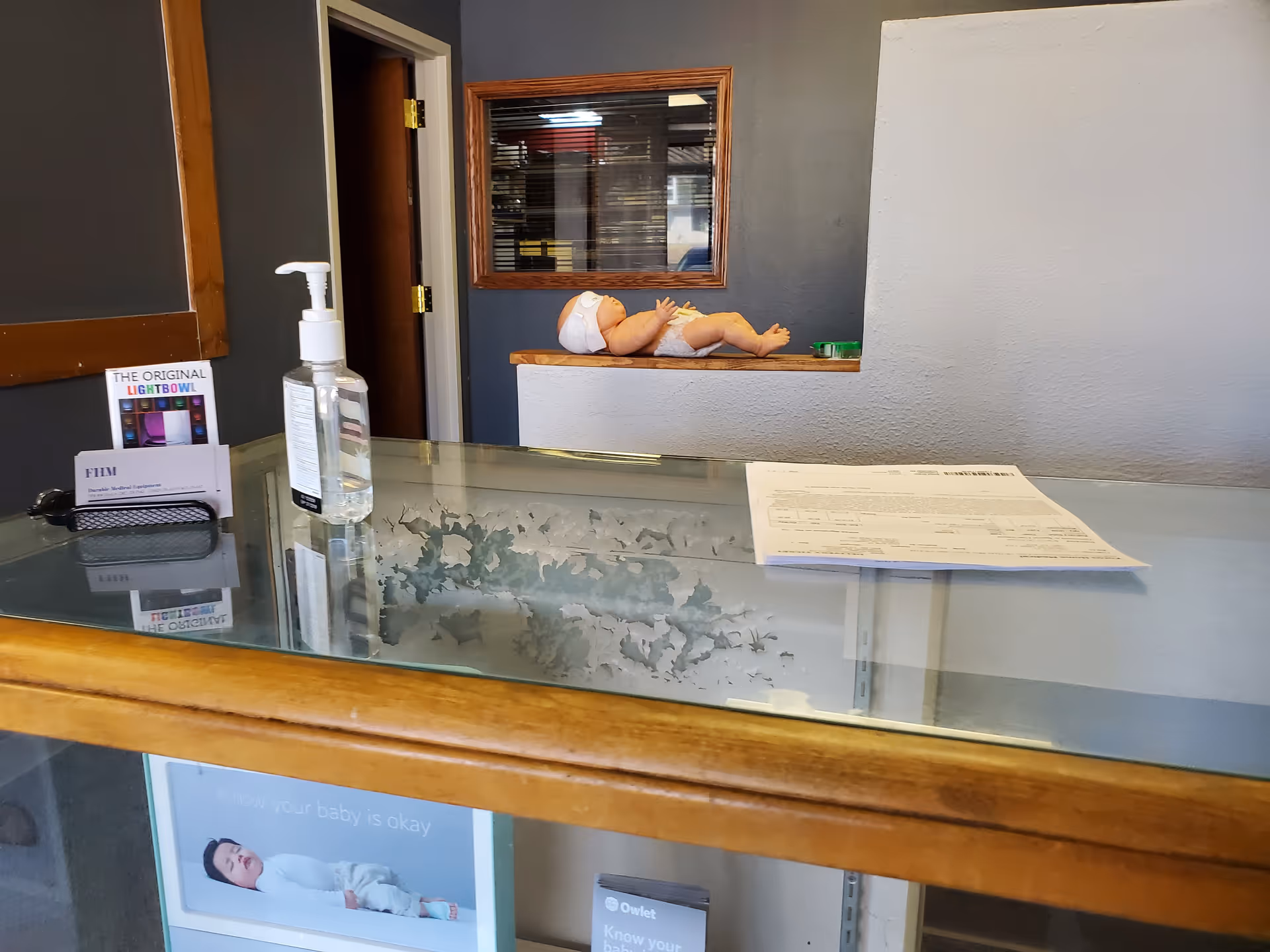 Reception counter inside a facility with a baby mannequin on a shelf behind.